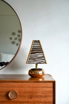 Rudi Table Lamp by Tantri Mustika on a timber chest of drawers: a black and white marbled shade edged in gold, over a gold lustre base