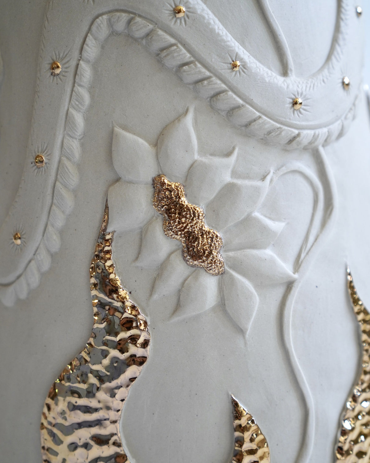 Detail of the carved Ukiran table lamp by Tantri Mustika: a serpent, a flower and gold lustre flames in white stoneware