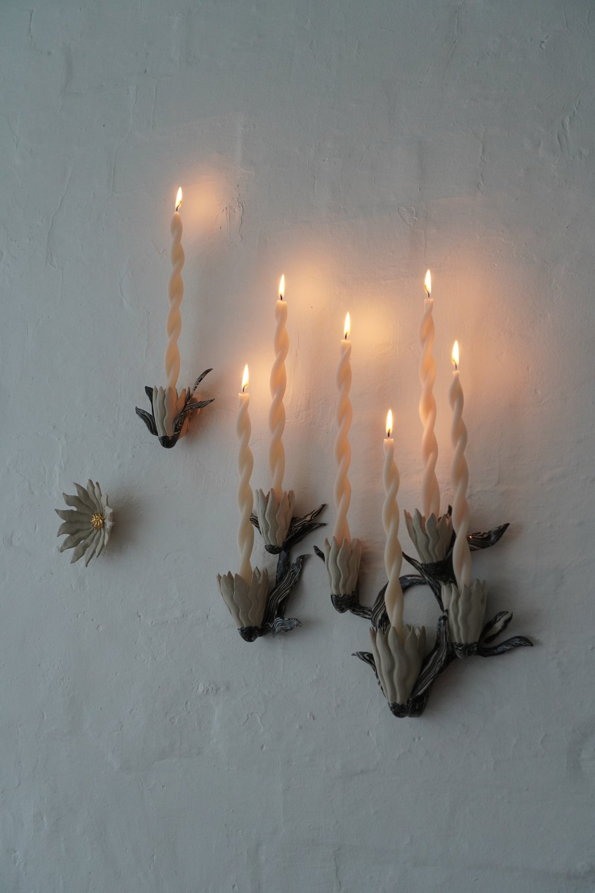 Unfurled by Tantri Mustika: candle sconces in stoneware and gold lustre, flowers at different stages of bloom, lit, Flame 2024