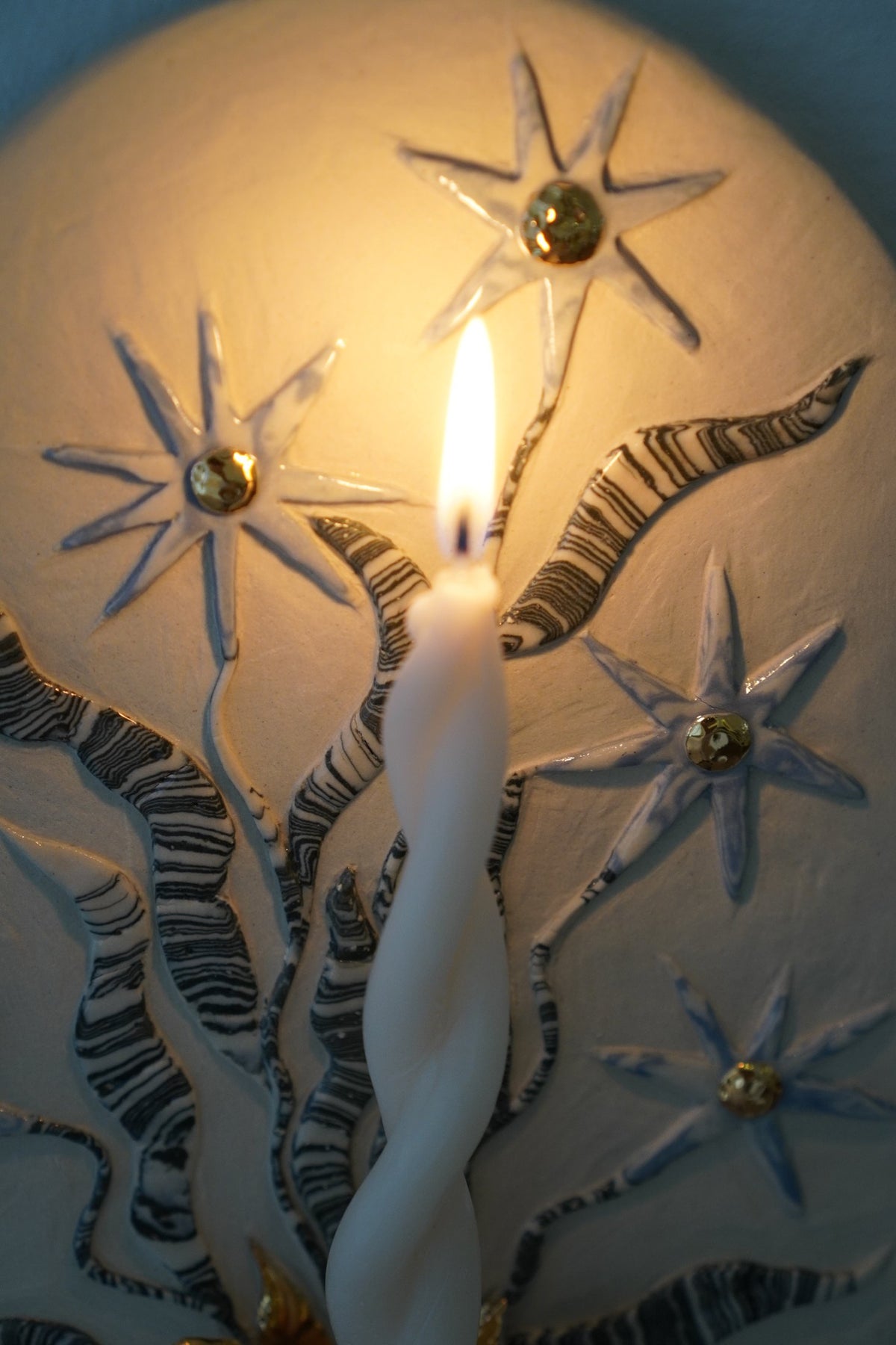Detail of the star flower candle sconce by Tantri Mustika, lit, Flame 2024