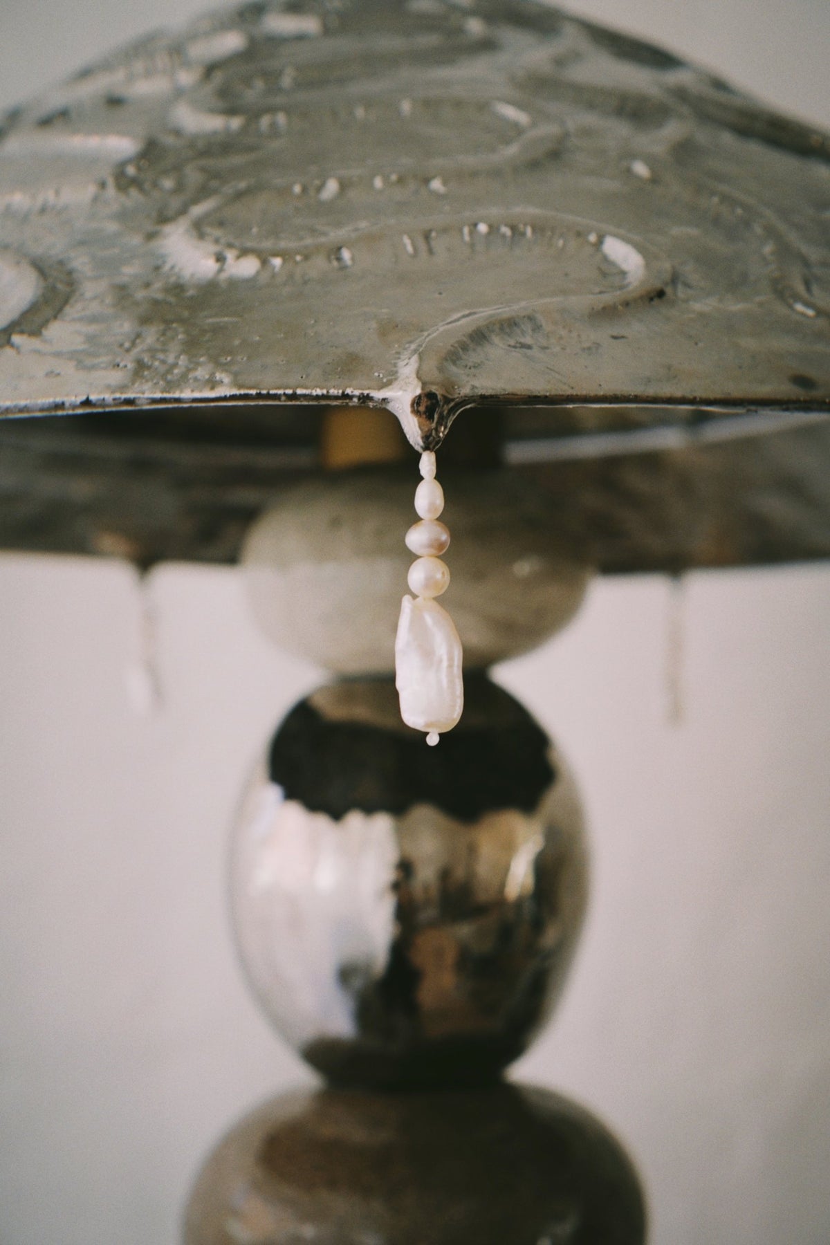 A baroque pearl hanging below the shade of the Flow State floor lamp by Tantri Mustika