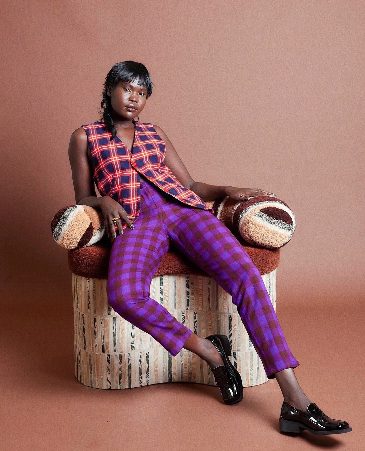 Model seated on the Kidney chair: tufted upholstery by Megan McNeill on a base clad in marbled ceramic by Tantri Mustika, FOND 2022