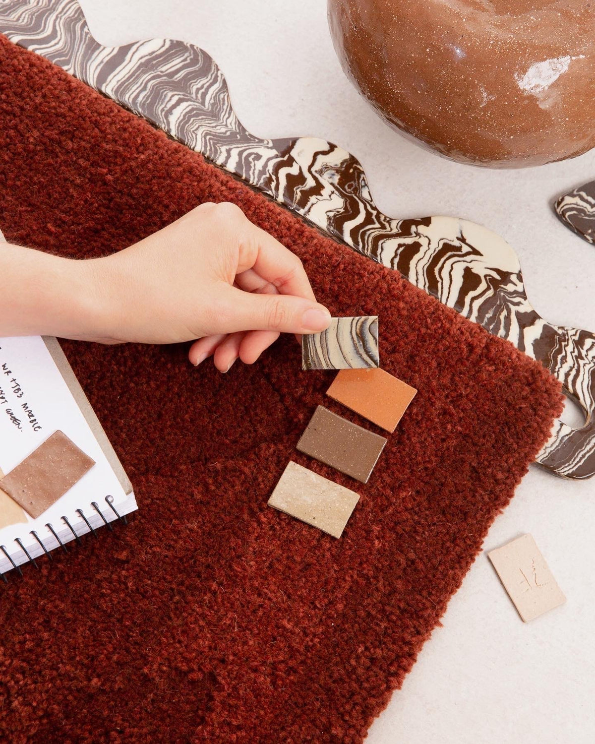 Ceramic and textile samples laid on a tufted rug while planning FOND, 2022