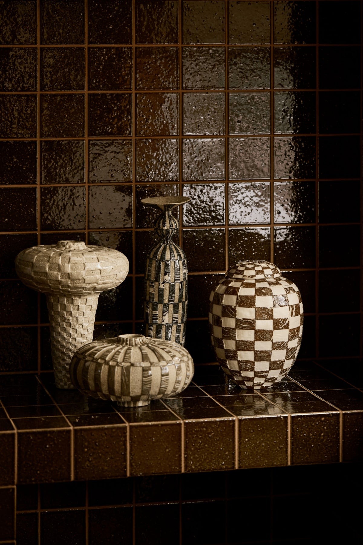 Four vessels by Tantri Mustika, checked and woven in texture, on the brown-tiled fireplace at The View by Studio Shields