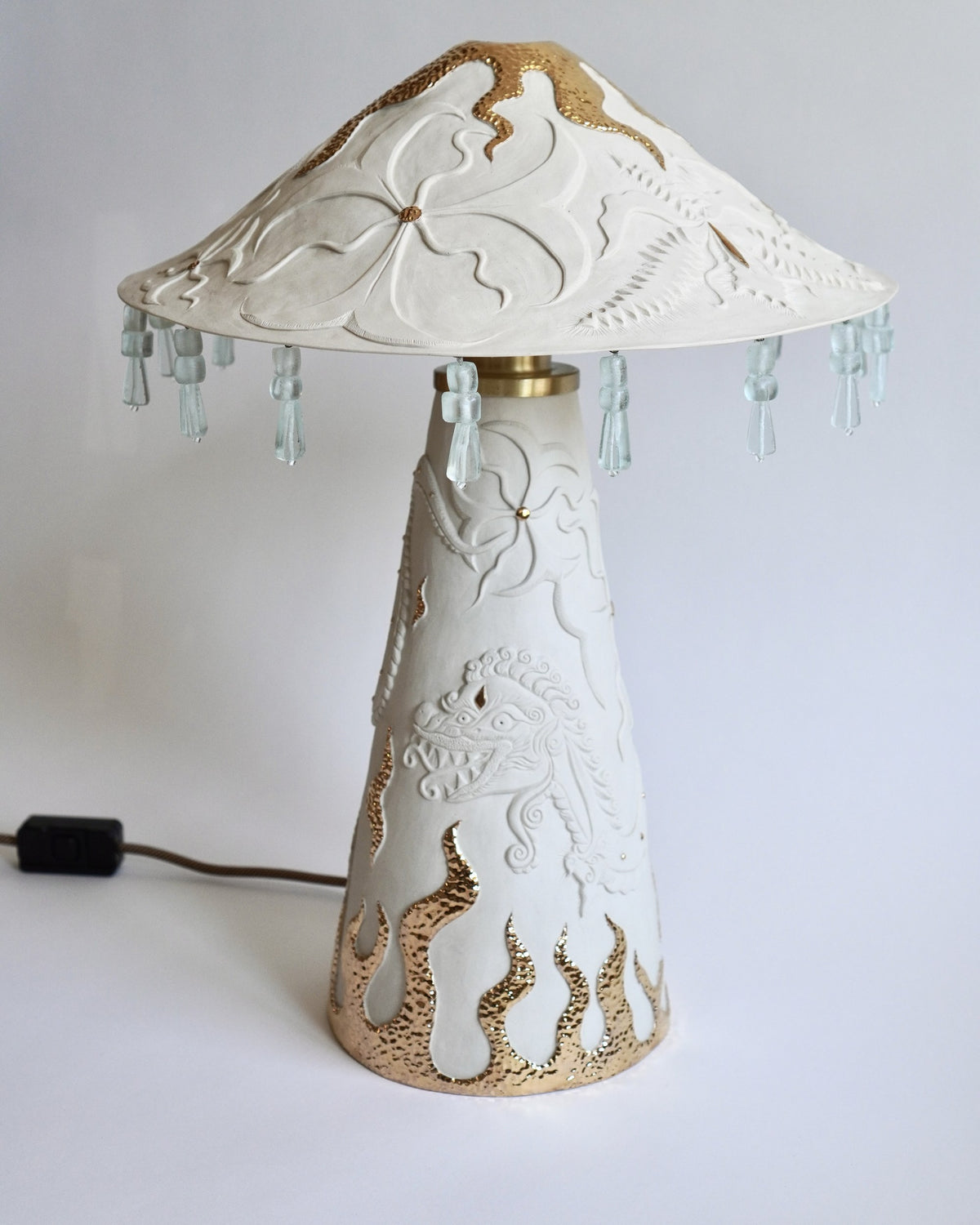 Ukiran Table Lamp by Tantri Mustika: carved white stoneware with gold lustre flames and a beaded shade